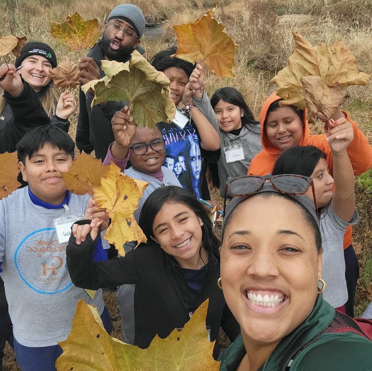Group of people holding autumn leaves in a field