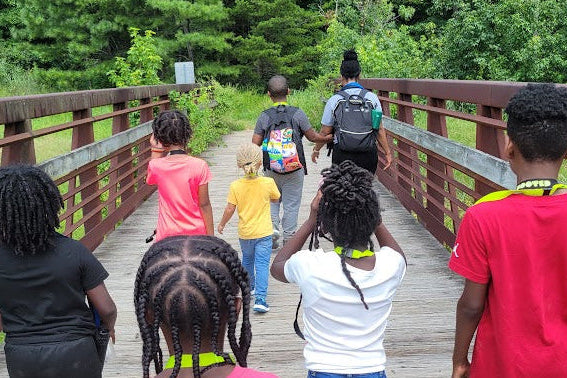 Group of people walking on a wooden bridge in a forested area