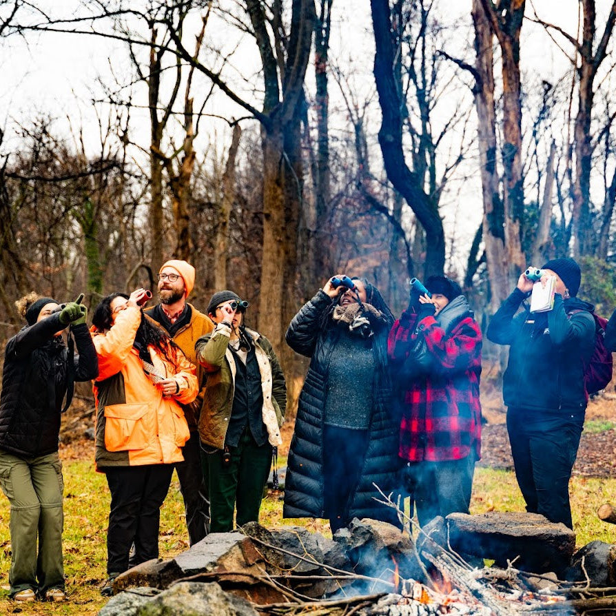 Group of people taking photos of a bonfire in a forest